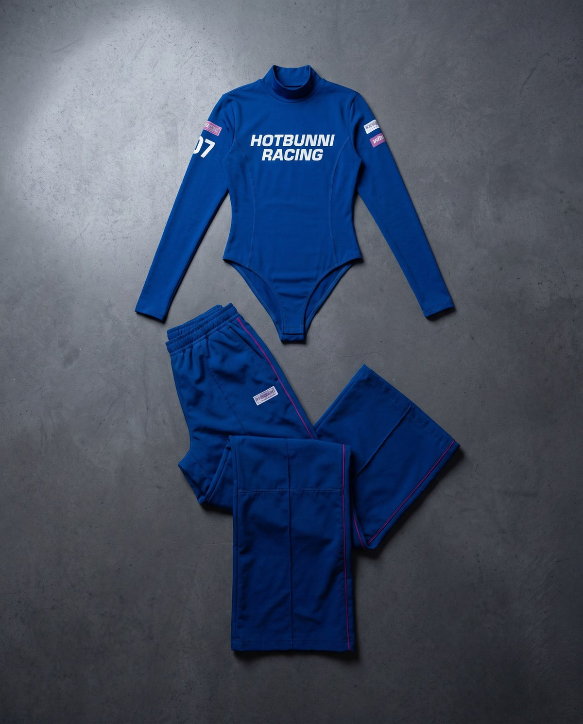 Komplettes Racing-Set in Team-Blau: Langarm-Body mit Rollkragen und Wide-Leg-Rennhose nebeneinander